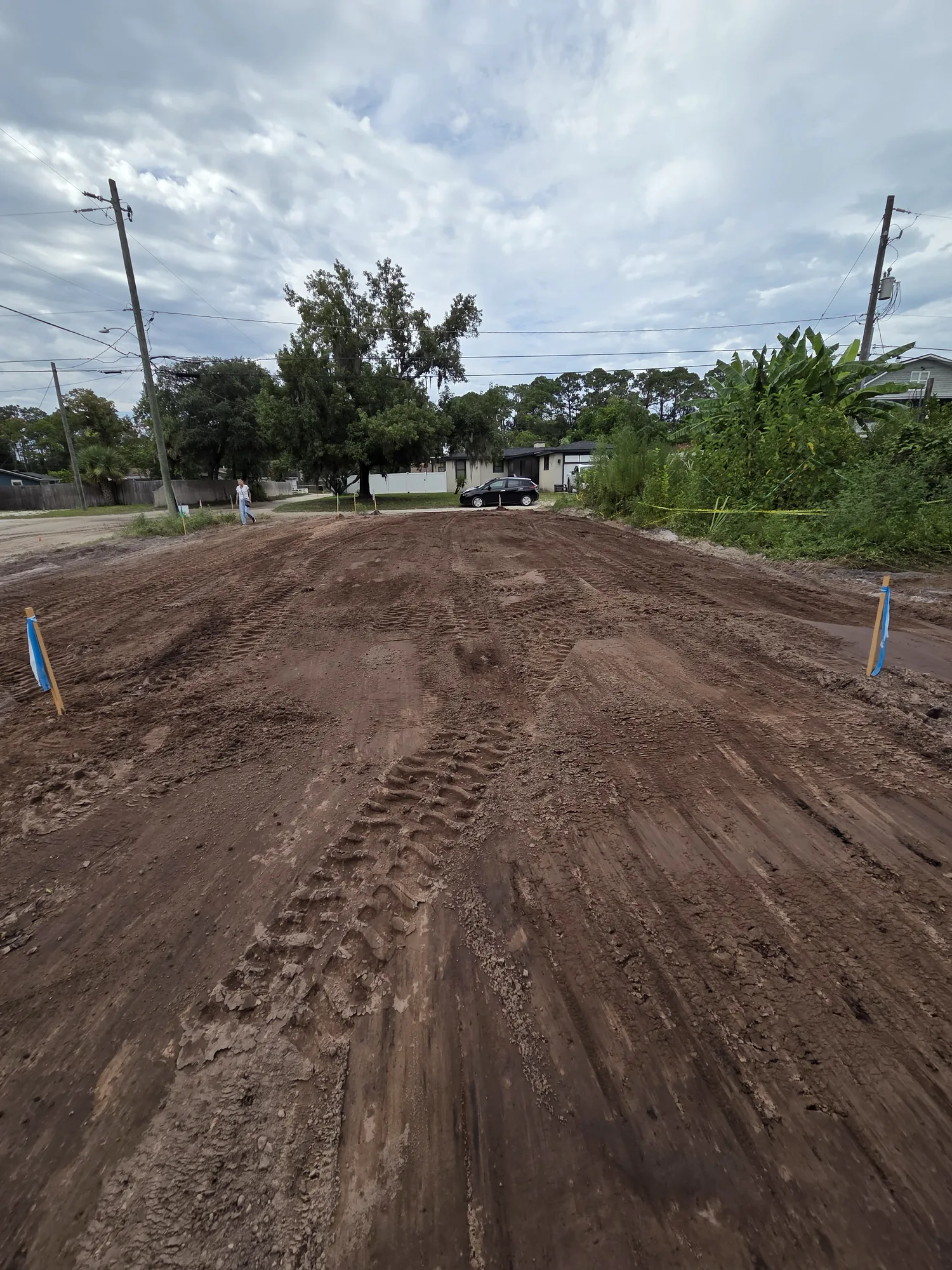 Freshly graded dirt pad with survey stakes on a North Florida residential lot