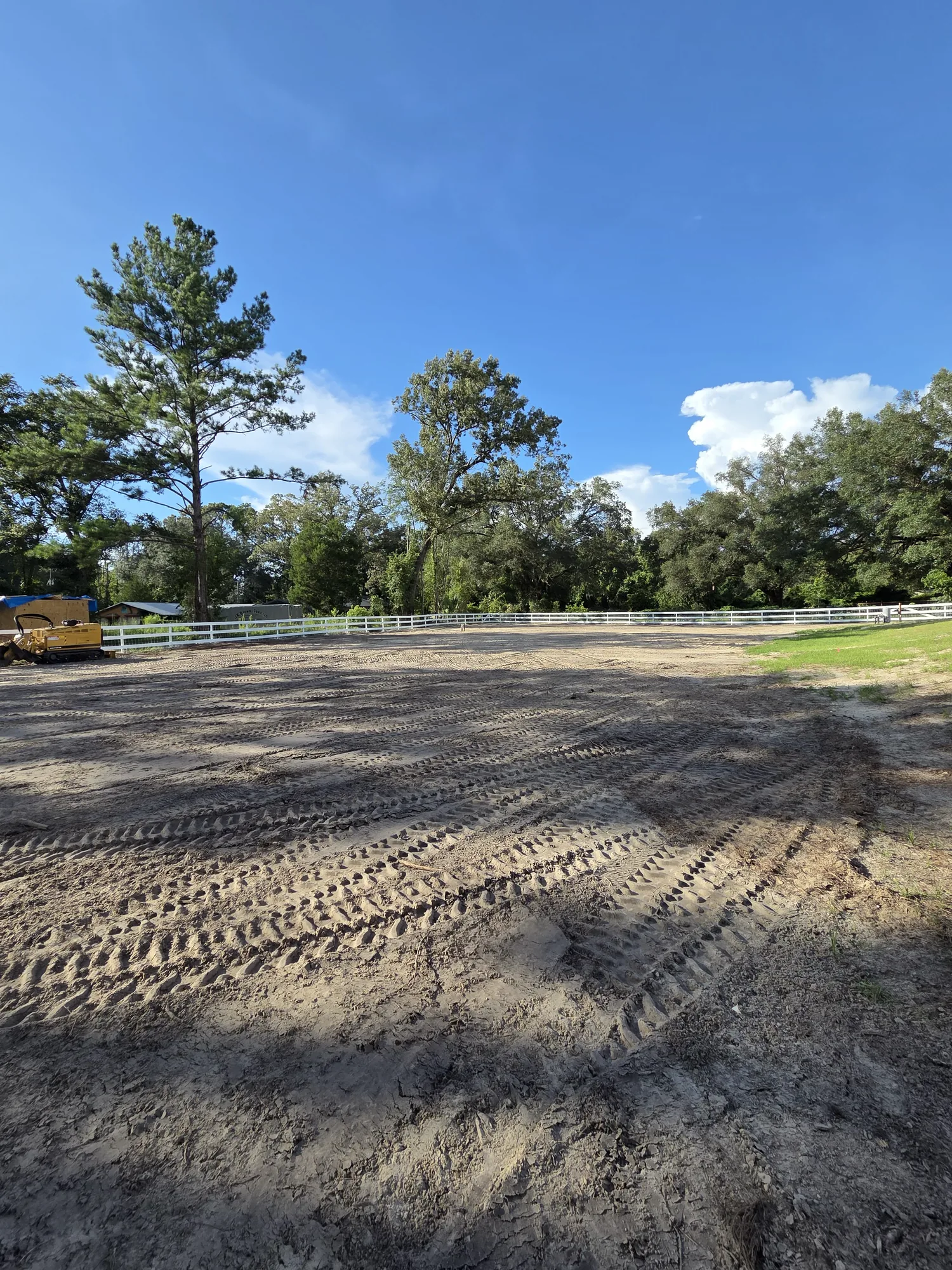 Large graded sand pad along a white ranch fence on a North Florida property