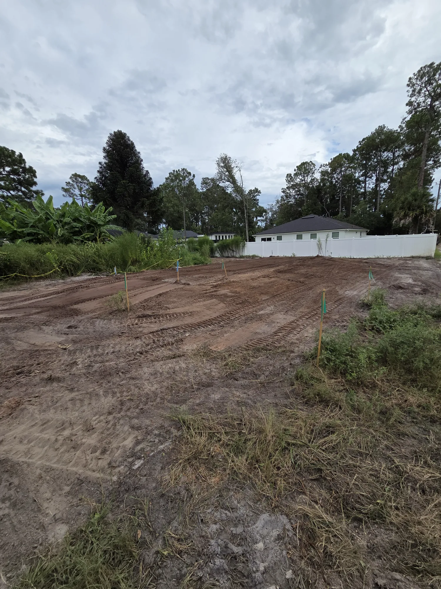 Residential lot cleared and graded flat next to a finished home in North Florida